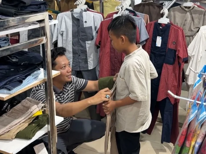 BERBAGI - Ketua AJK Theo Bernadhi saat memilih celana untuk salah satu anak yang ikut kegiatan AJK berbagi