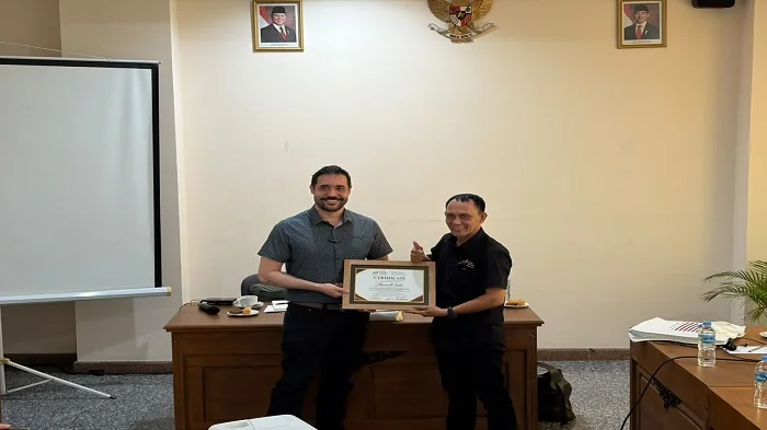 Penyerahan Cinderamata dari Ketua AMSI Kaltim, Ahmad Yani pada Maxwell Scott pakar dan Penasihat Tata Kelola AI (AI Governance) asal Amerika Serikat pada kegiatan diskusi ertajuk “Teknologi AI dan Dampaknya terhadap Trust dan Integritas Media” yang digela
