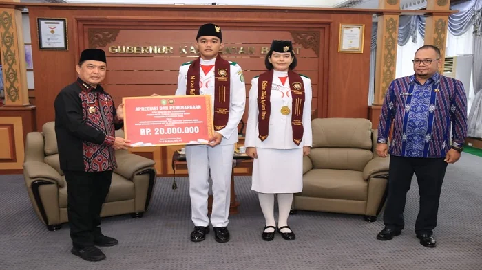PENGHARGAAN - Gubernur Ria Norsan memberikan penghargaan  kepada Celine Olivia Apriani Theo yang bertugas sebagai Pembawa Baki pada upacara pengibaran bendera Merah Putih, serta Mirza Rafi Navazani yang bertugas sebagai Pembentang Bendera pada upacara pen