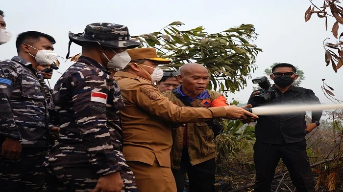 SEMPROT - Gubernur Kalimantan Barat Ria Norsan saat menyemprotkan air untuk memadamkan api  saat meninjau lokasi kebakaran hutan dan lahan (karhutla) di Parit H. Mukhsin, Kabupaten Kubu Raya, Selasa (1/9/2026)