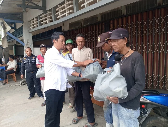 BAGI SEMBAKO - Satu di antara anggota AJK saat memberikan sembako gratis kepada pekerja harian lepas yang berada di sekitaran kota Ketapang. (Dok Nur Imam Satria)